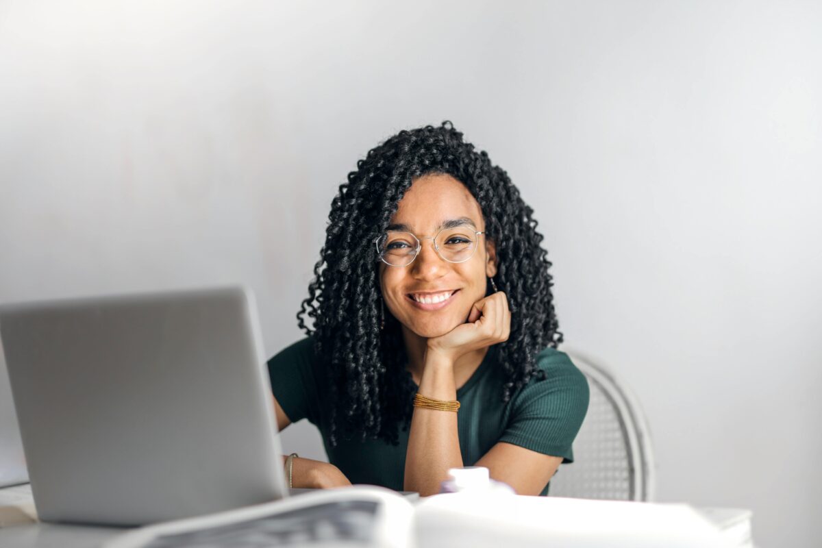Woman sitting at a desk in front of a laptop, smiling at the camera.