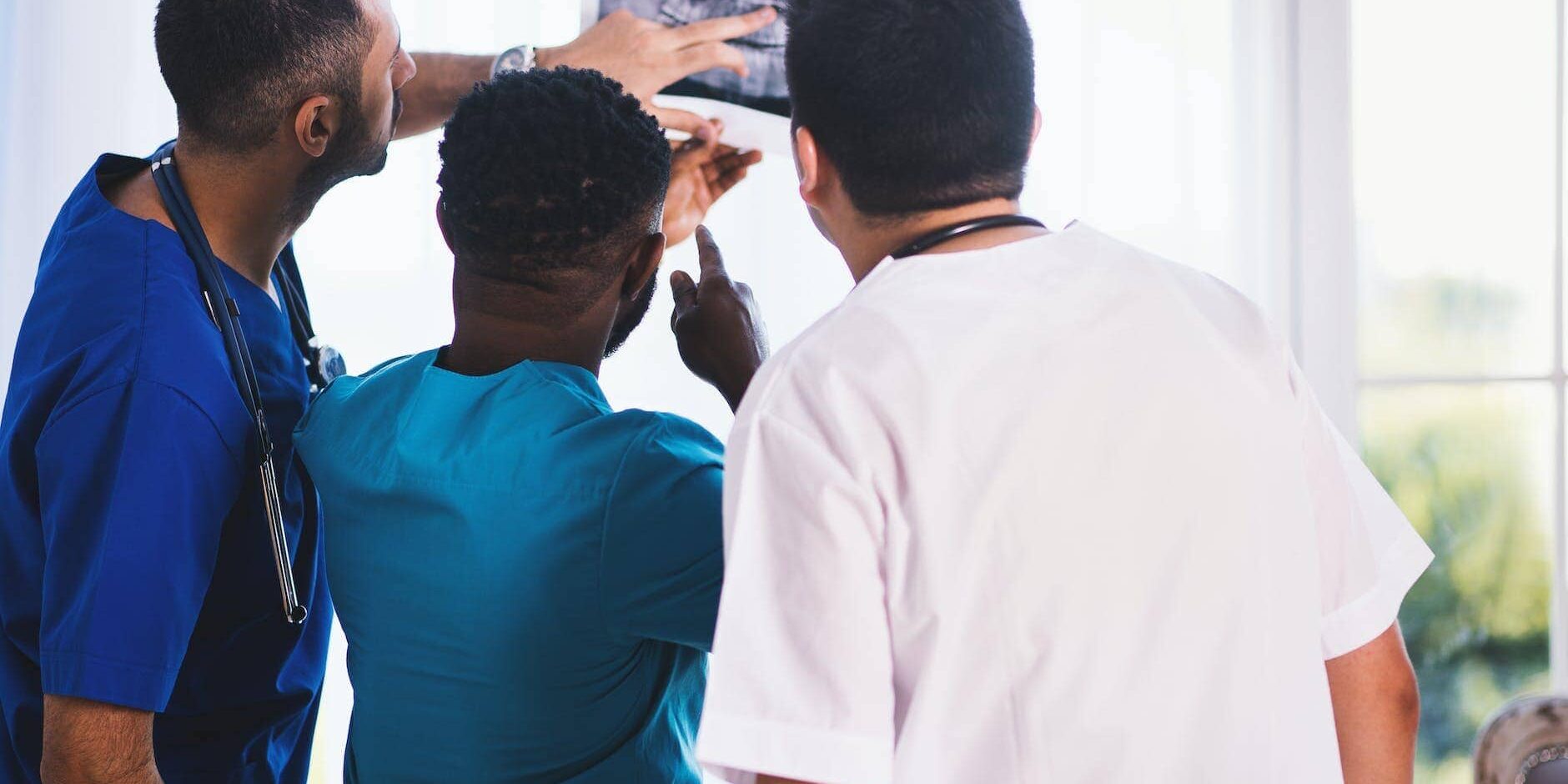 three person looking at x ray result