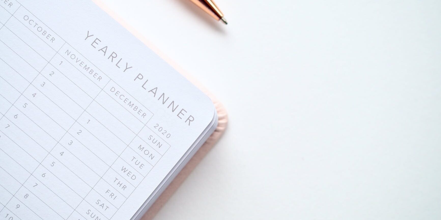 close up photo of yearly planner beside a pen