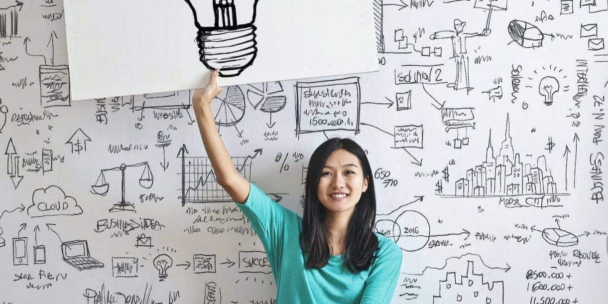 woman draw a light bulb in white board