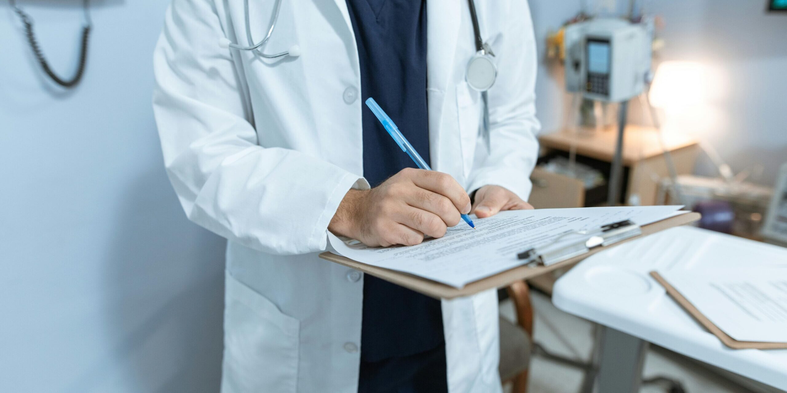 Hospital provider writing on clipboard.