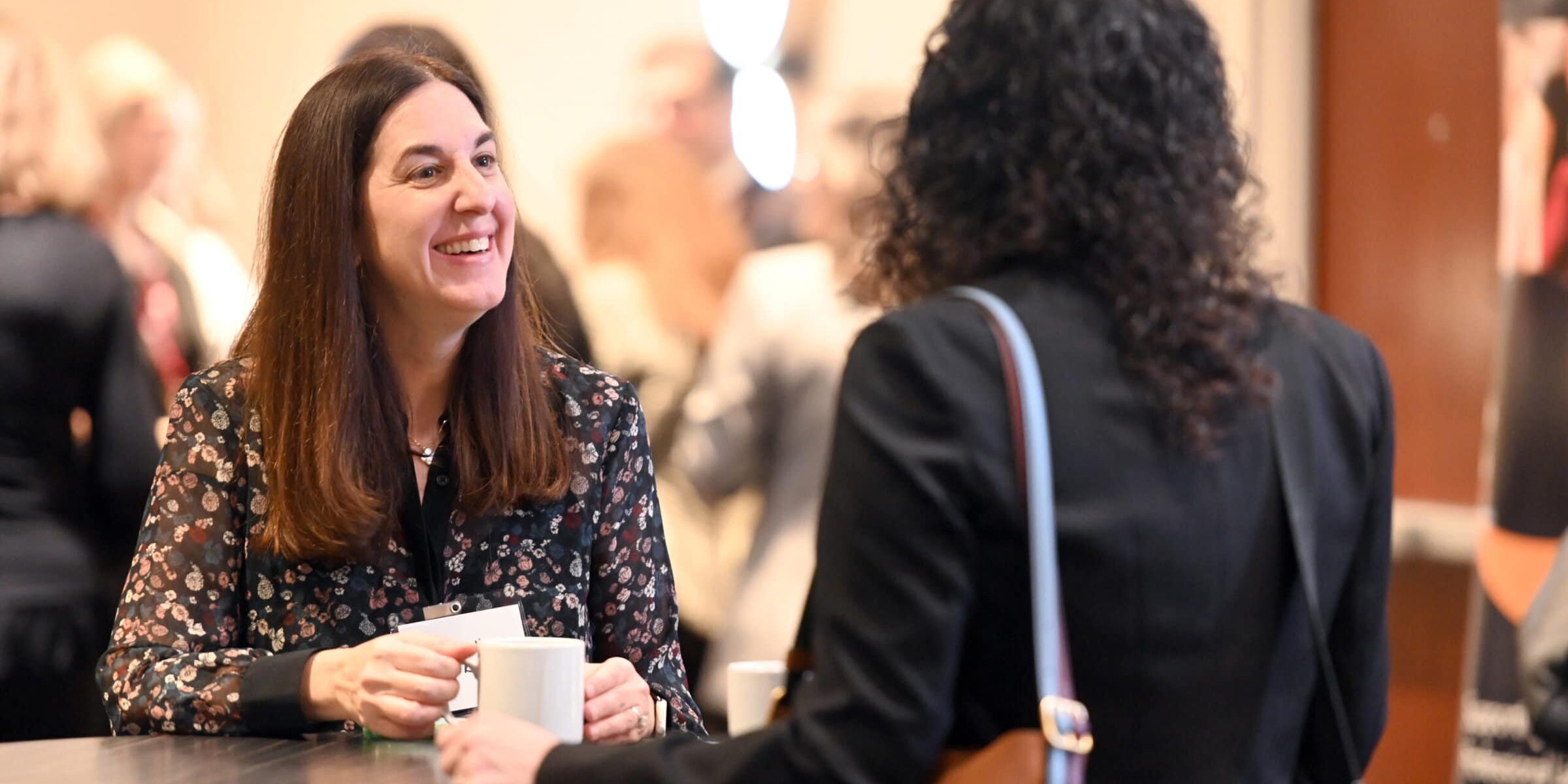 Two women talking over a cup of coffee at a PLUS Foundation Luncheon