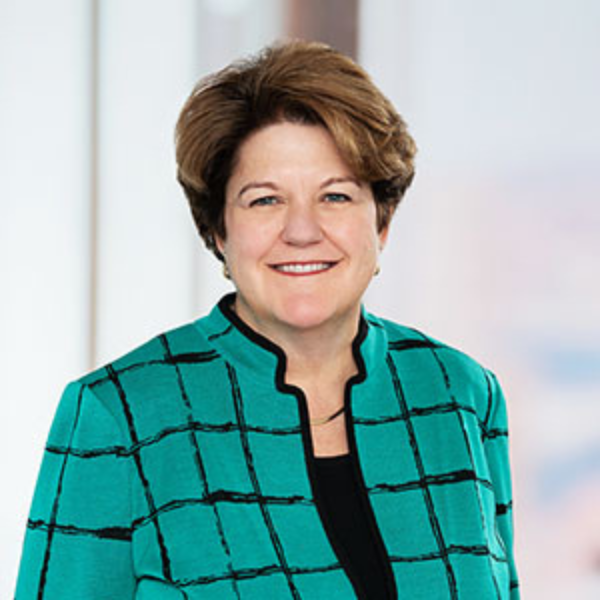 Headshot of Nancy Adams. Wearing a green and black sweater smiling from the chest up