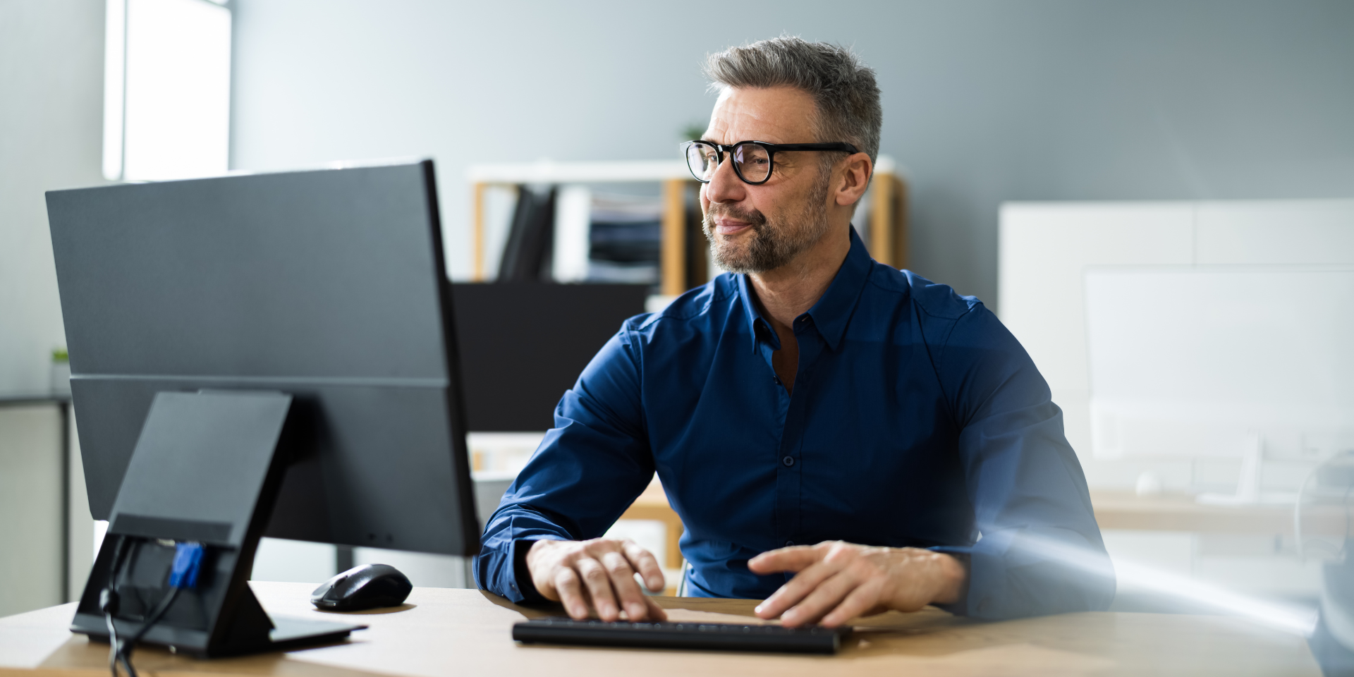 Image of a man sitting in front of a desk top computer