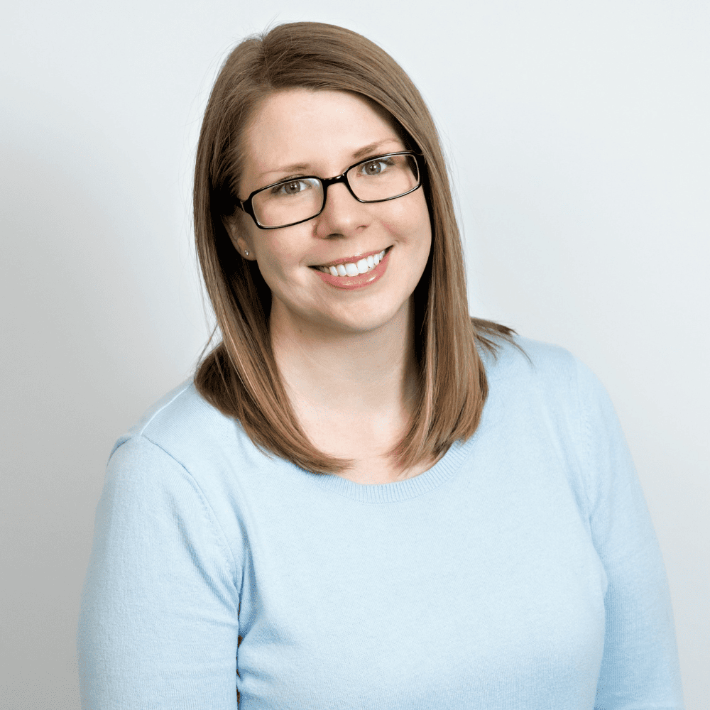 Headshot of Marissa Glaser from the shoulders up, smiling with glasses in a light blue shirt with shirt brown hair