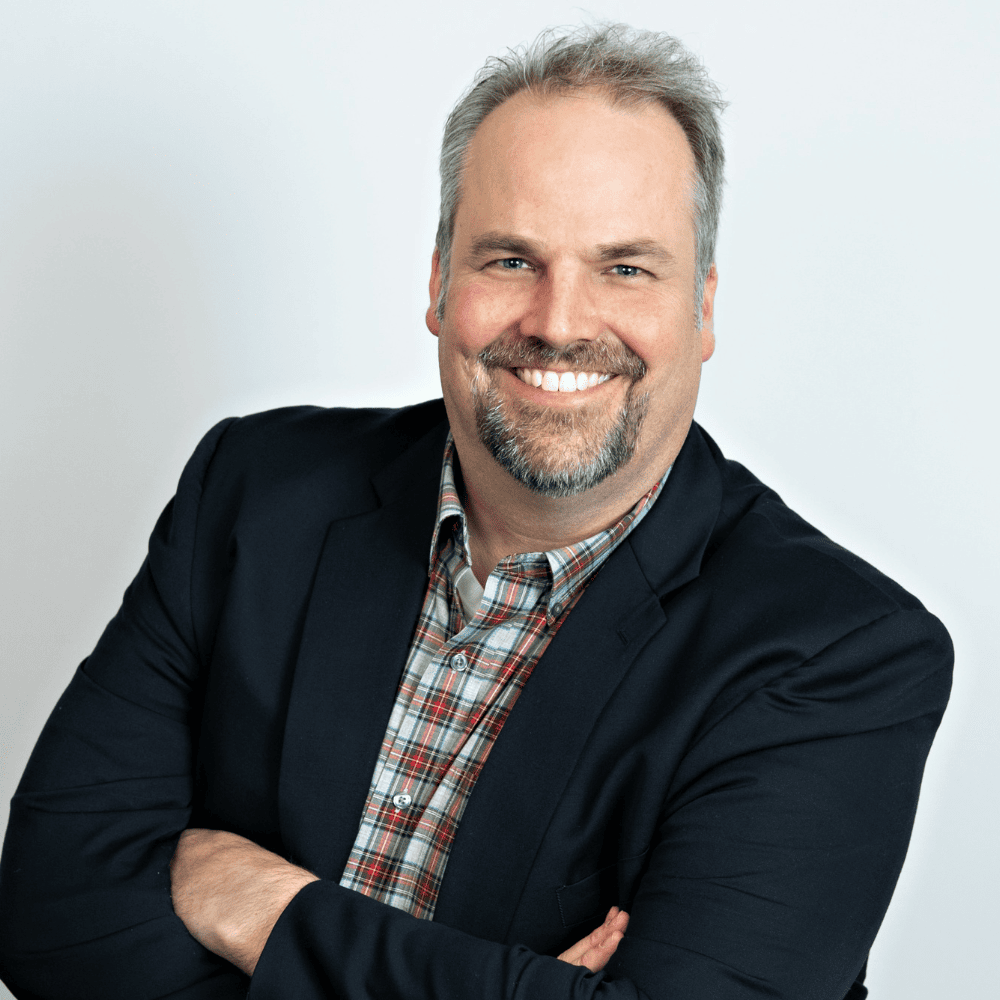 Headshot of Scott Billey from the shoulders up, smiling, in a black blazer with short gray hair