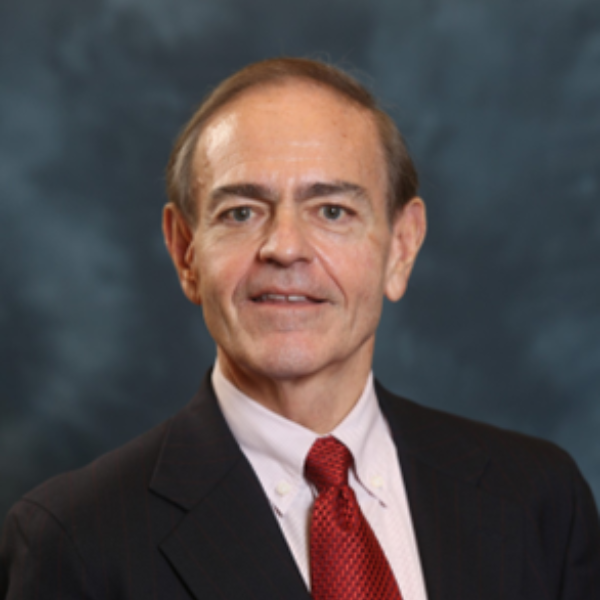 Headshot of David Stewart. Wearing a suit and red tie smiling from the chest up.