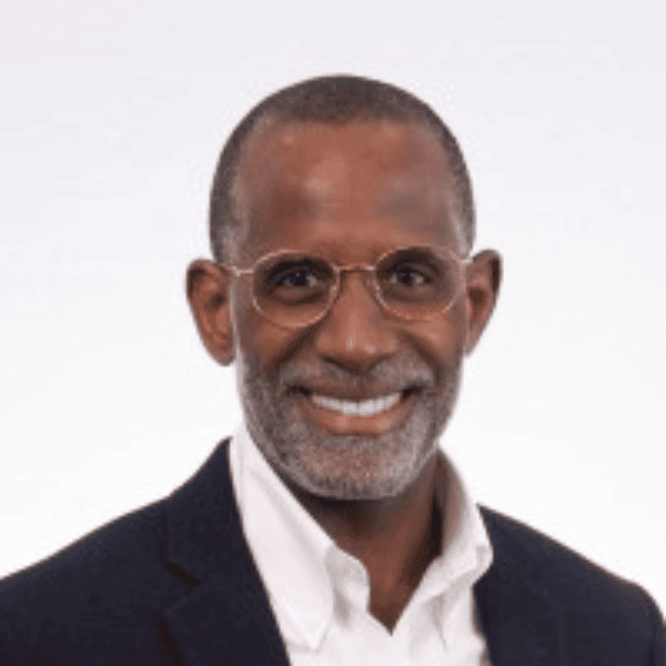 Headshot of William Wharton. Wearing a black and white suit and glasses from the chest up