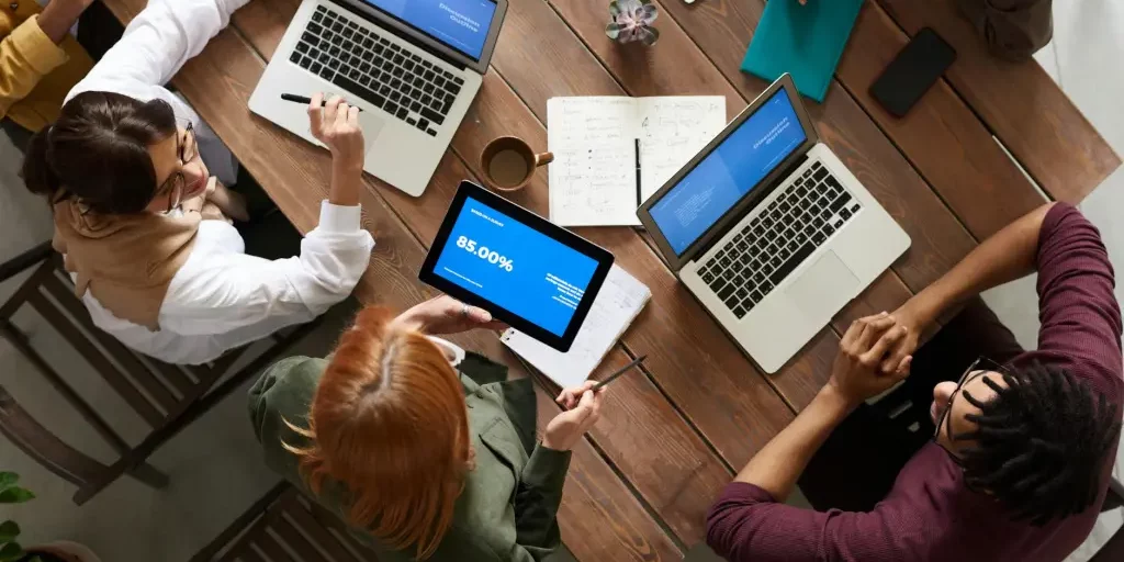 People sitting around a table with laptops and notebooks